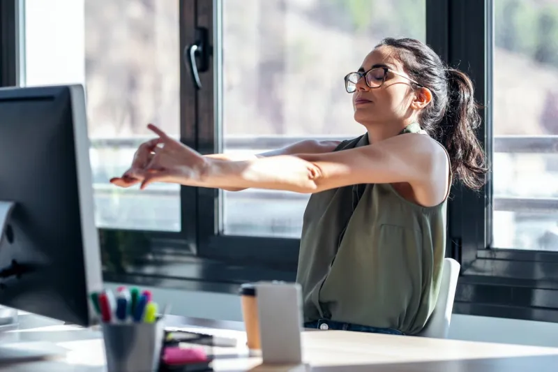 shot of tired businesswoman stretching body for relaxing while working with computer in the office