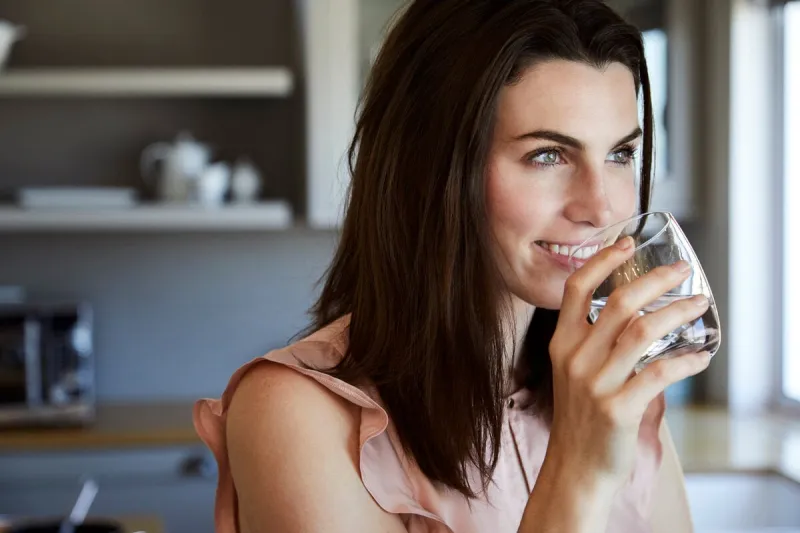 beautiful woman drinking water and smiling in kitchen