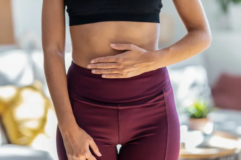 close-up of sporty woman with her hands on her belly in front of the mirror