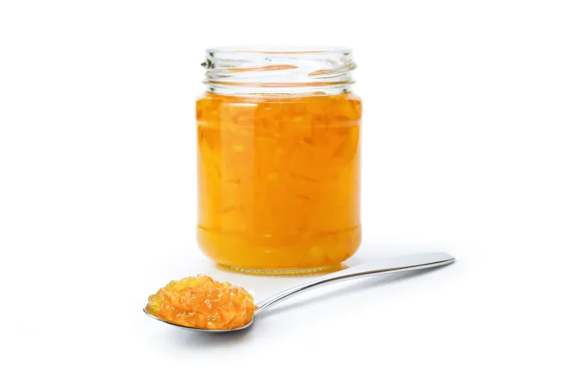 orange marmalade jam in glass jar and spoon isolated on white background