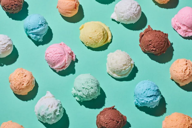 top view of seamless background of assorted scoops of ice cream arranged in lines on blue table