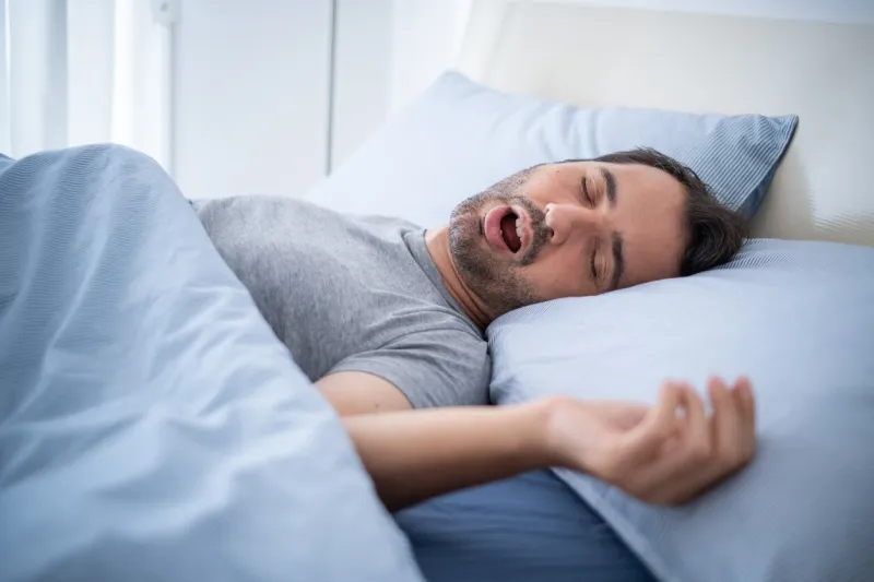 man snoring loudly in his bed while sleeping