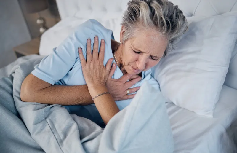 heart attack, senior woman and chest pain, anxiety or medical emergency in her bedroom heartburn, stress or stoke of elderly person cardiology, breathing and lung problem with healthcare risk