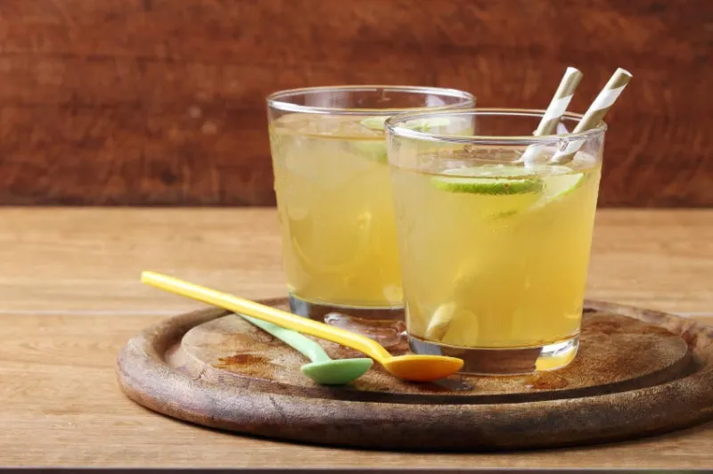 boisson gazeuse froide d'or de chaux et de miel avec de la paille d'or sur la planche de bois