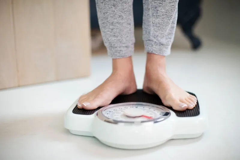 close up of woman standing on bathroom scales at home