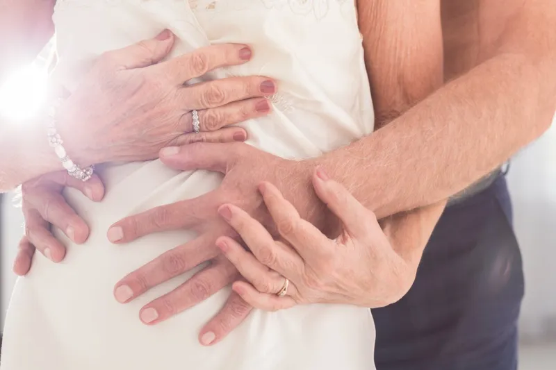 cropped shot of a man's hands caressing his wife's body