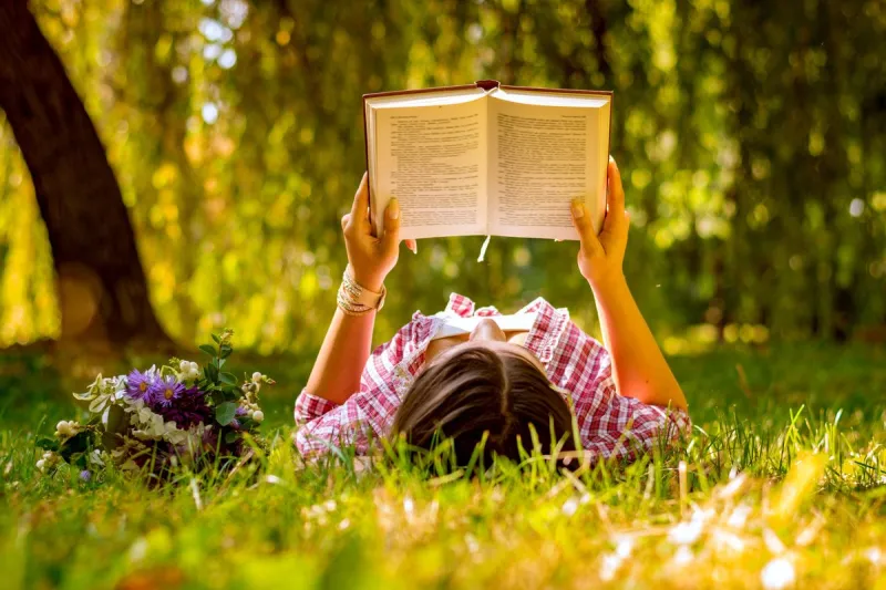 young woman reading a book in the park with flowers