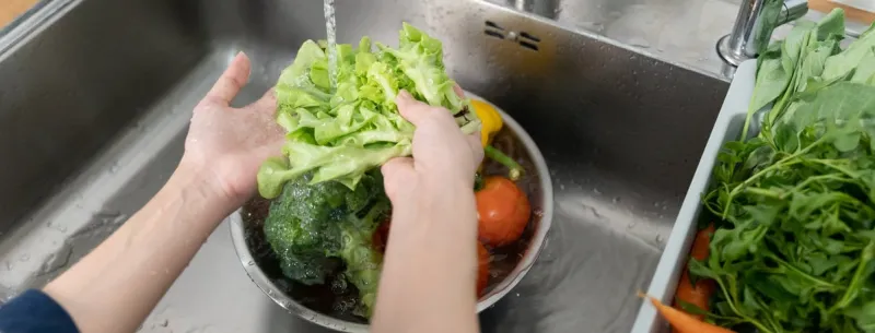 close up of hands people washing vegetables by tap water at the sink in the kitchen to clean ingredient prepare a fresh salad