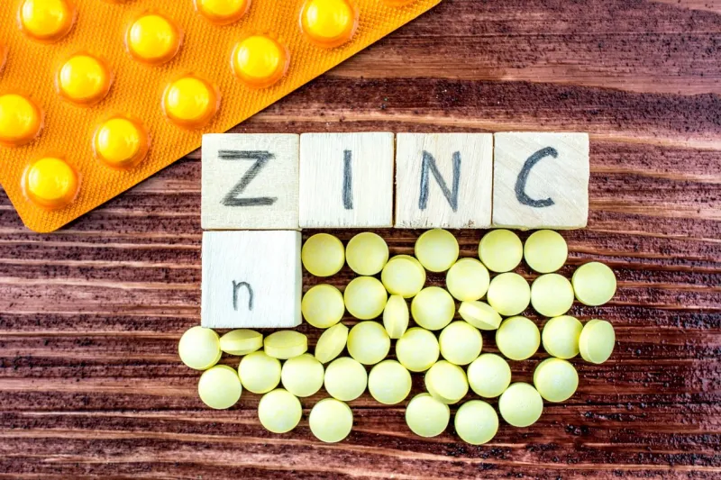 yellow pills, blister pack and wooden cubes on a wooden table they all symbolize zinc (zn) element from the periodic table