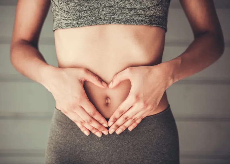 cropped image of slim afro american girl in sportswear showing heart on her stomach