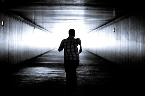 black and white conceptual imageman is running out of the tunnel into the light motion blur he is determined to get out of darkness into the light there is hope and determination