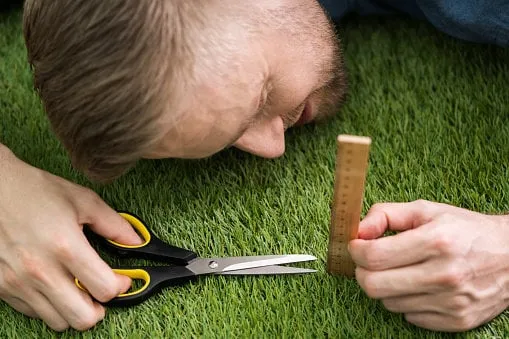 close-up of a man cutting green grass measured with ruler