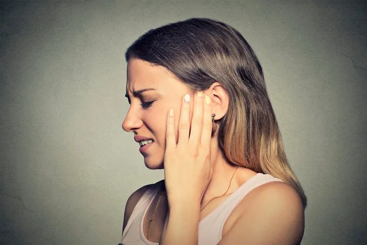 tinnitus closeup side profile sick young woman having ear pain touching her painful head isolated on blue background