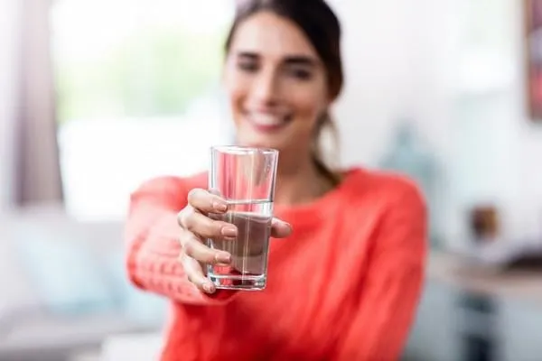 jeune femme montrant le verre à boire avec de l'eau