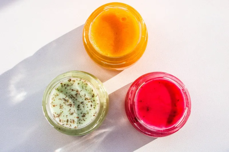 multicolored honey in a jar on the white desk colored jars with sweet honey or jam - green, yellow and red