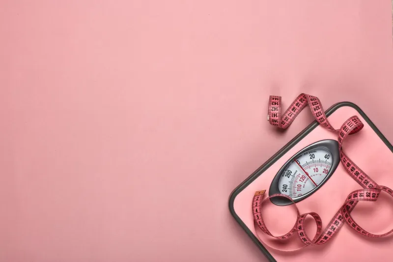 female fitness still life scales and measuring tape on pink background mockup planning of diet and trainings top view with copy space healthy lifestyle concept slimming