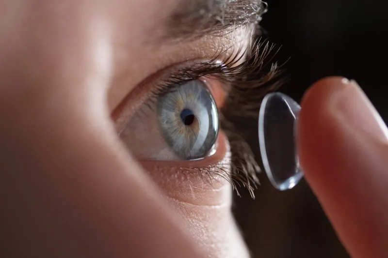 close-up of a man putting contact lenses on blue eye concept of