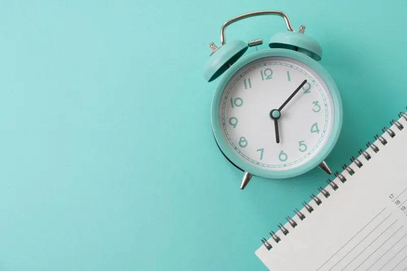 close up of calendar and alarm clock on the green table background, planning for business meeting or travel planning concept
