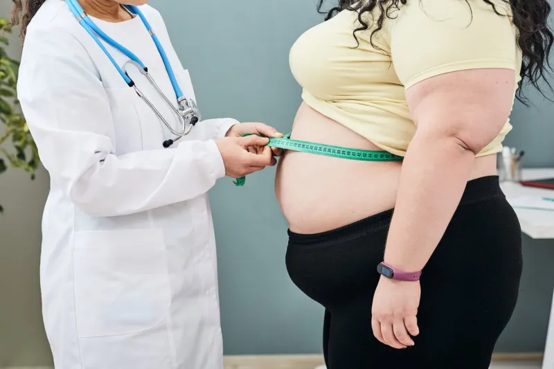 obesity, unhealthy weight nutritionist inspecting a woman's waist using a meter tape to prescribe a weight loss diet