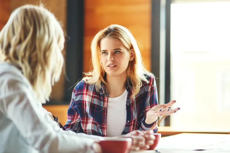 two young female friends chatting over coffee in cafe blonde women discussing issues