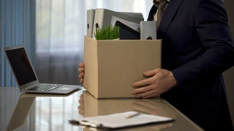 employee putting his stuff from work desk in carton box, leaving job, retirement