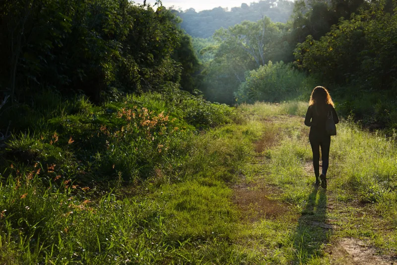 woman in black clothes and boots walking along a dirt street close to several farms in the region the photo was taken in the city of pilar do sul, state of são paulo in brazil