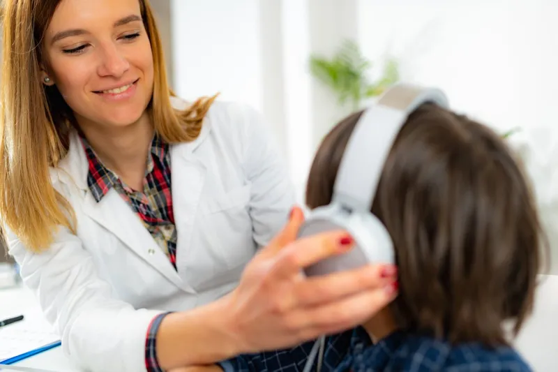 doctor wearing hearing aid to boy in hospital