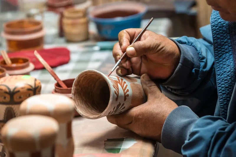 peruvian artisan while paints a typical terracotta vase