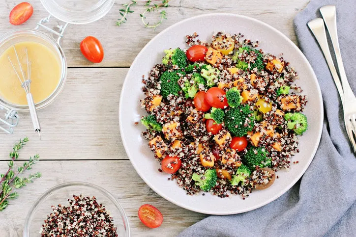 quinoa salad with broccoli,sweet potatoes and tomatoes on a rustic wooden tablesuperfoods conceptselective focus
