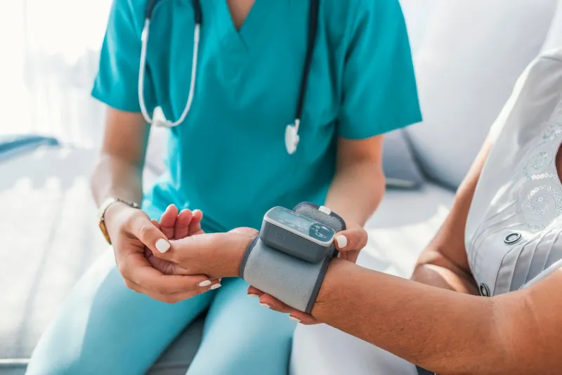 caregiver measuring blood pressure of senior woman at home kind carer measuring the blood pressure of a happy elderly woman in bed in the nursing home