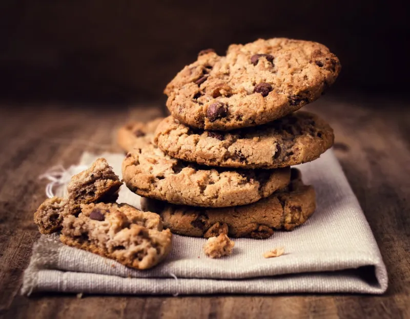 chocolate chip cookies on linen napkin on wooden table stacked chocolate chip cookies close up