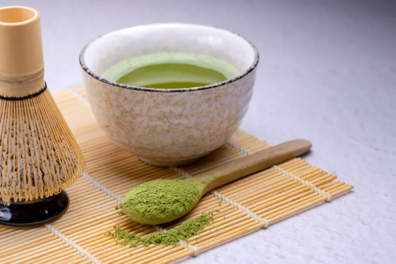 matcha tea traditional japanese drink green tea, in ceramic dishes, in natural dishes matcha tea in a bowl and scattered dry tea powder close-up, copy space, gray background, selective focus