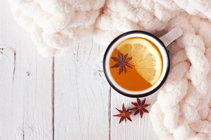 lemon spice tea, top view on a white wood background with blanket cozy fall or winter theme