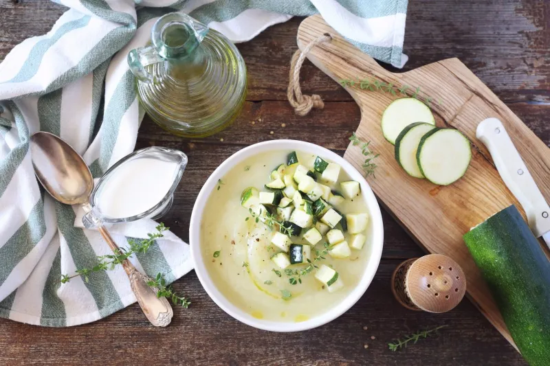 zucchini vegretable cream soup, thyme and olive oil dressing on wooden background rustic style, top view