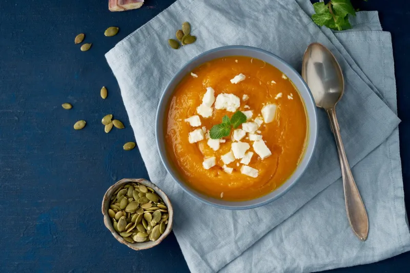 pumpkin cream soup with a groat cheese, autumn homemade food, dark blue background, top view fodmap diet, lchf vegetarian menu, clean eating recipe copy space