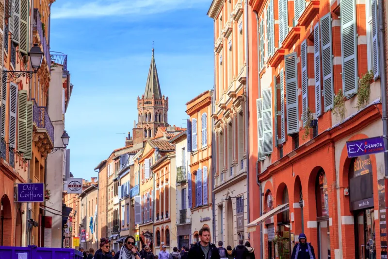 touolouse, france  april 01, 2018  people walking in the street in te city of toulouse, with san sernin basilica in the background