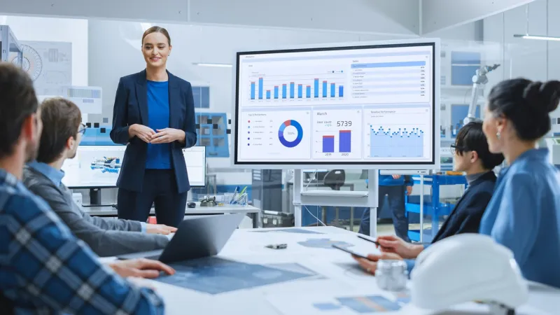 modern industrial factory meeting  confident female engineer uses interactive whiteboard, makes report to a group of engineers, managers talks and shows statistics, growth and analysis information