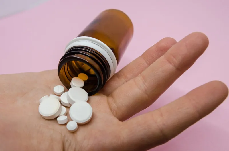 medical pills spilling out of pill bottle on the hand medicine concept isolated on the pink background cure your pain with capsules treatment stay healthy and take tablets
