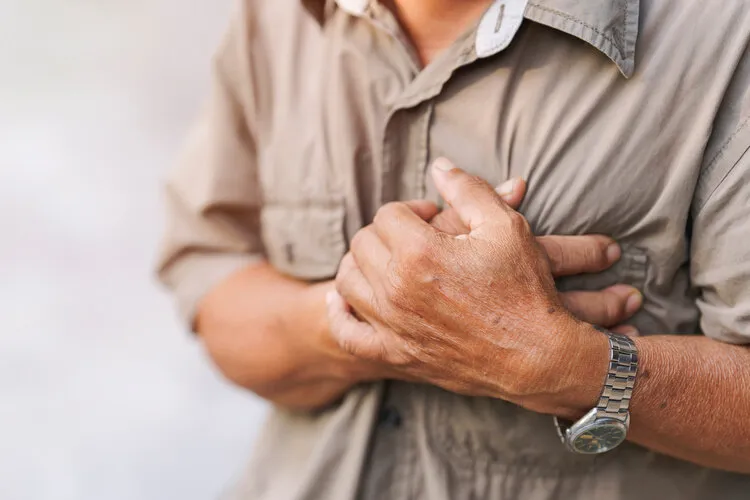 close-up of an elderly man's hand held his chest in pain concept of heart disease