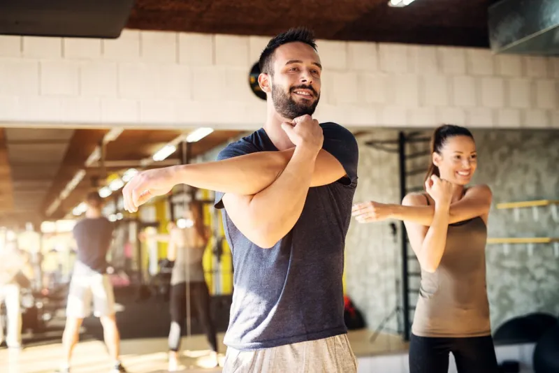 strong young smiling athletes stretching in a gym
