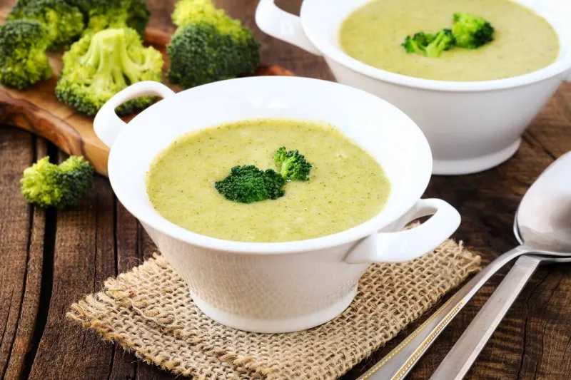 healthy vegetarian cream of broccoli soup in white bowls on a rustic kitchen table