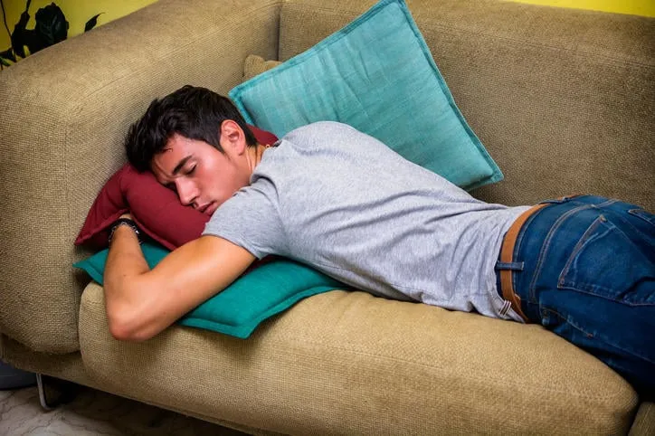 coup de trois quarts d'un jeune homme ivre dormant sur le canapé dans le salon de la maison