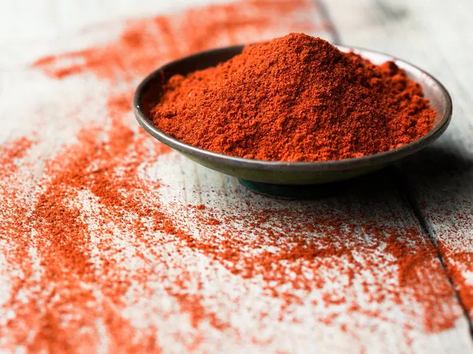 ground paprika in a bowl on wooden table
