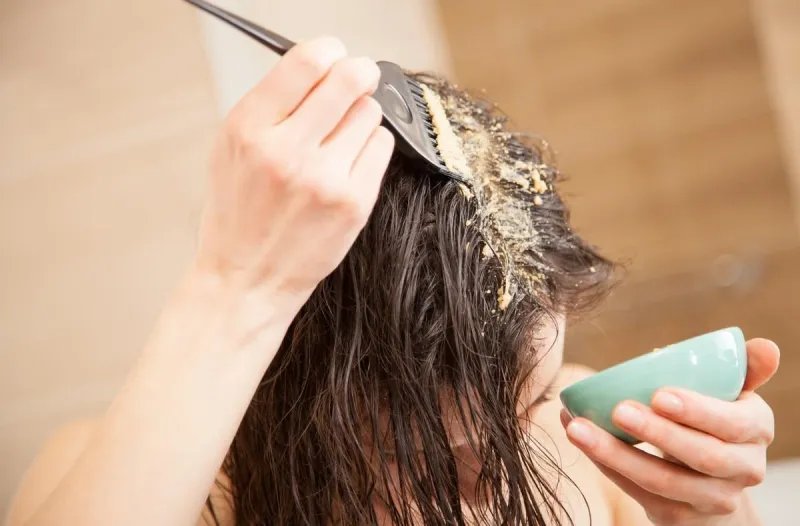 woman applying mask to hair roots to make them grow stronger and faster and to prevent hairloss
