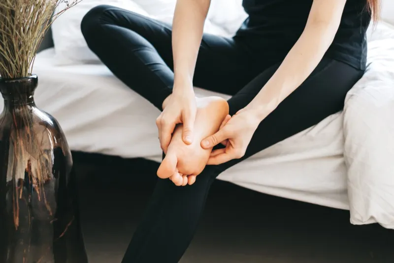 young woman massaging her foot on the white bed after training or hard working day healthcare concept high quality photo
