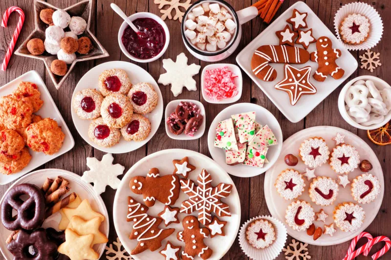 christmas table scene of assorted sweets and cookies top view over a rustic wood background holiday baking concept