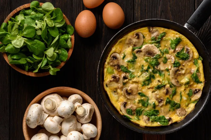 omelette with mushrooms and cheese, on dark wooden background
