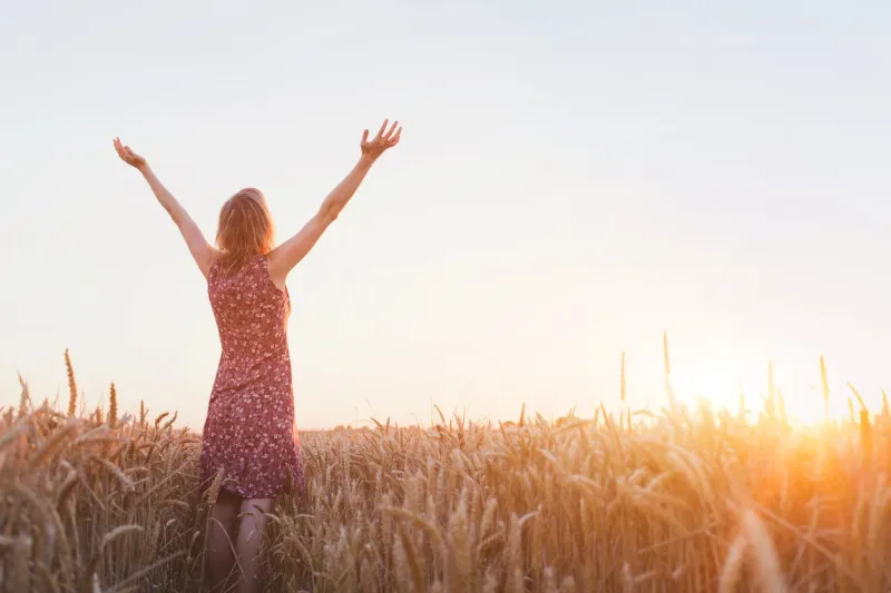 breathing, woman with raised hands enjoying sunset in the field
