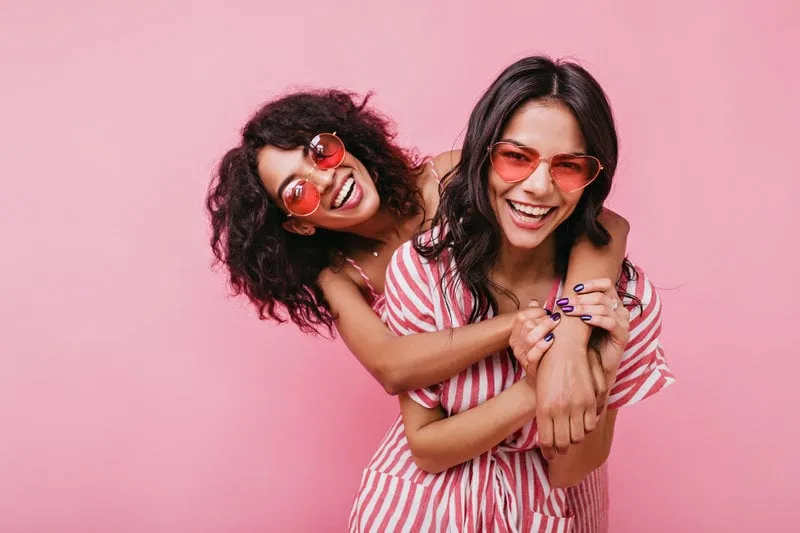 young, spectacular models vigorously pose for portrait in studio tanned sisters embrace and laugh in unusual glasses