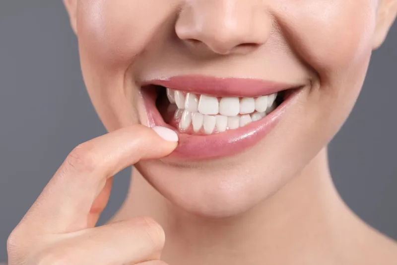 young woman showing healthy gums on grey background, closeup